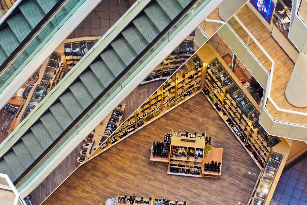 Menu Aerial view of a stylish shopping mall showcasing escalators and well-organized retail displays.